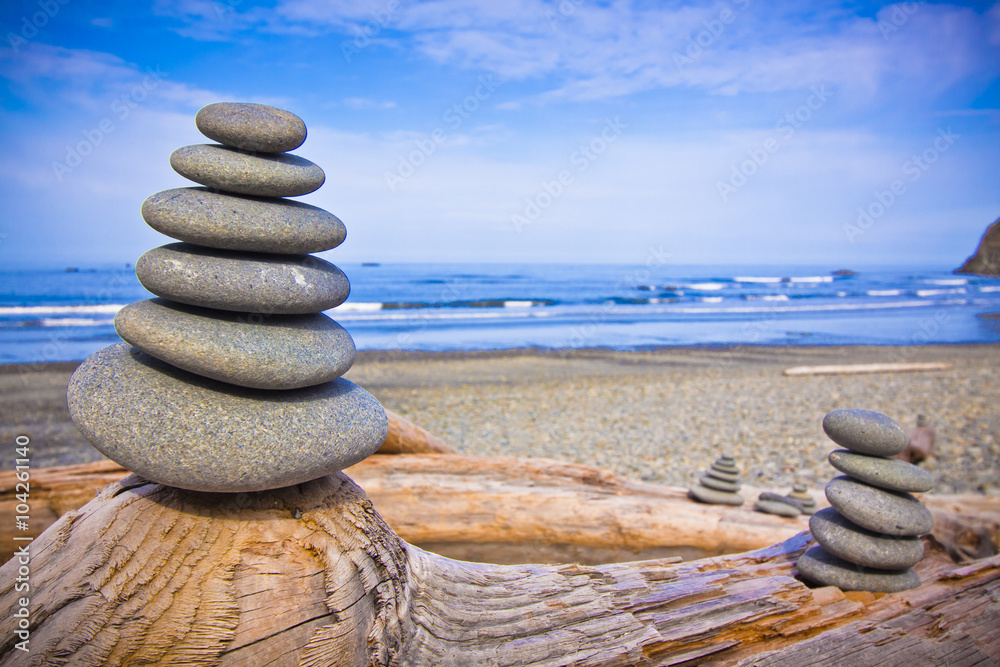 rocks balanced on the driftwood by seashore