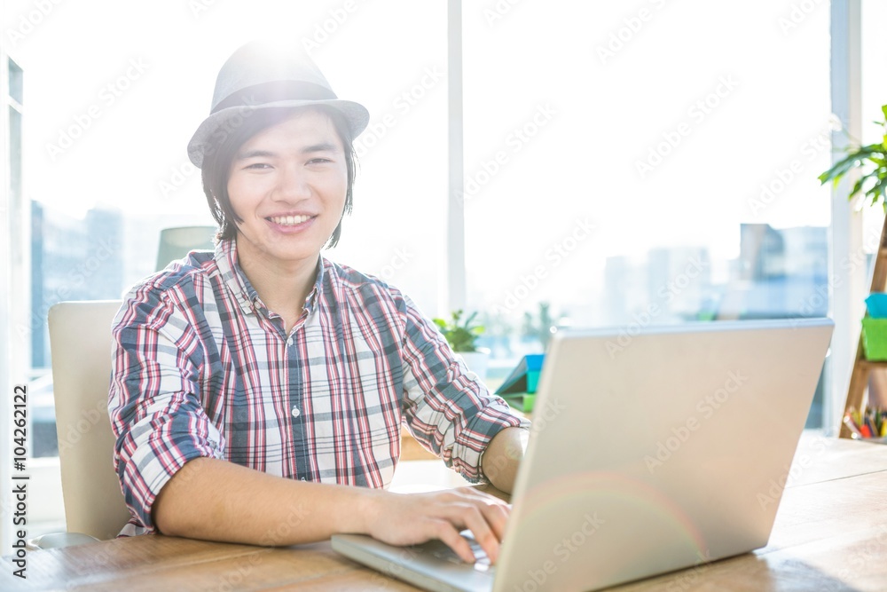 Smiling hipster businessman using laptop 