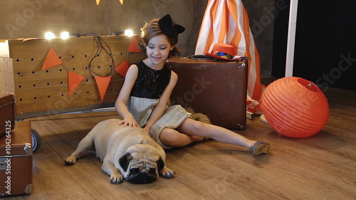 Little girl sitting near retro a suitcase with dog.