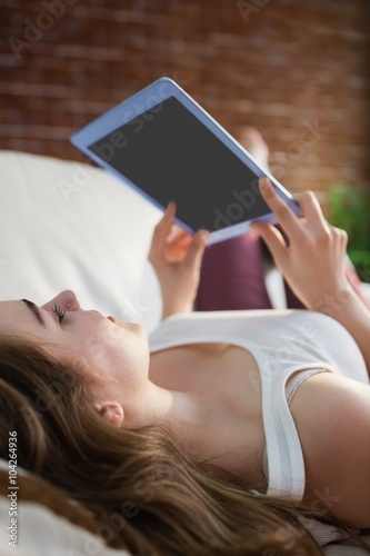 Pretty woman relaxing on couch with tablet