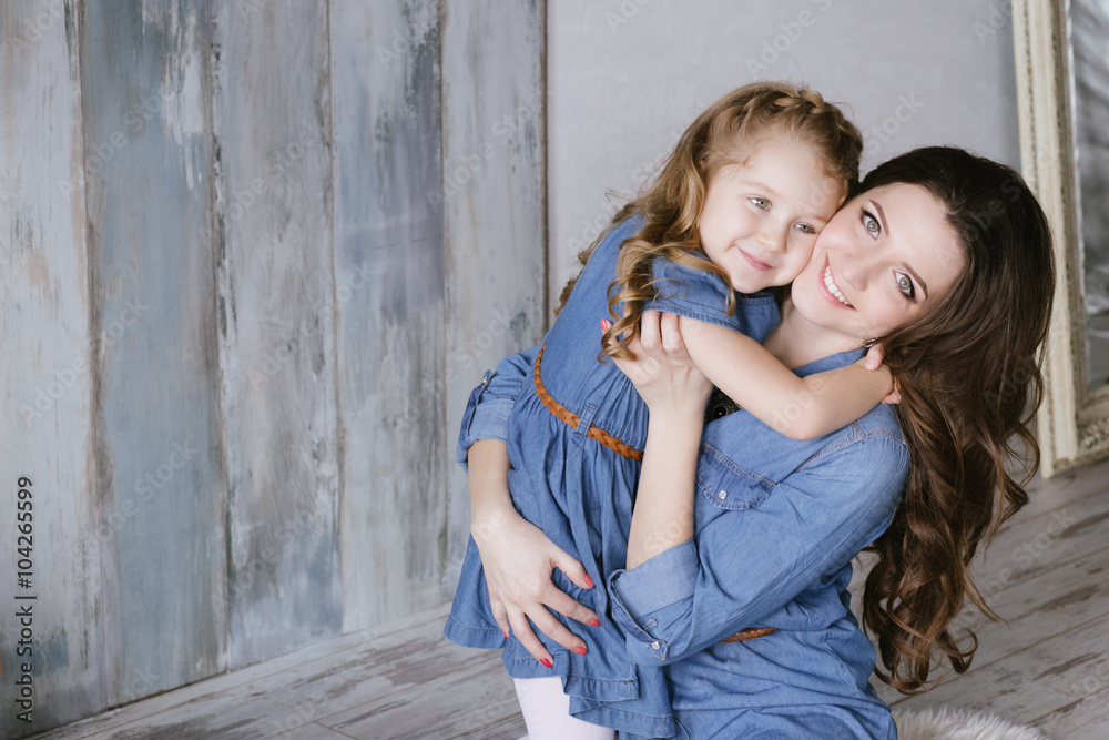 Happy family mother and little daughter hug and playing dressed in denim dress Happy family mother and little daughter hug and playing dressed in denim dress