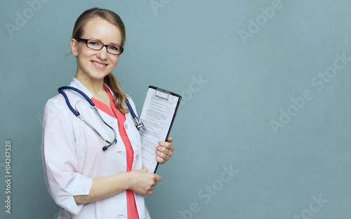 Doctor woman with medical records. Medical doctor woman with tethoscope white lab coat and glasses on a blue background smiling.



 photo