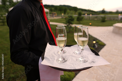 waiter holding four champagne glasses on a tray Fototapeta