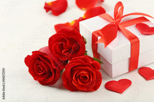Gift box  rose flowers and decorative hearts on light wooden background