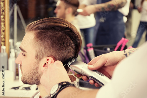 Professional barber making stylish man haircut