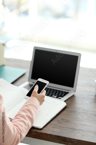 Woman working with notebook and using devices at the table in office