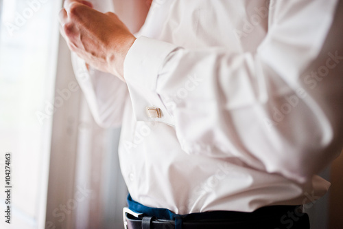 A young man wearing a cuff link  groom preparing for the wedding