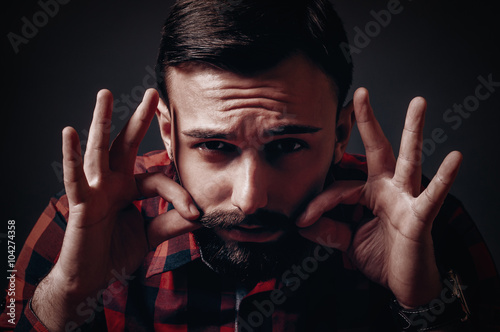 Portrait of lumber bearded style man pinching , twisting and waxing mustache with hands