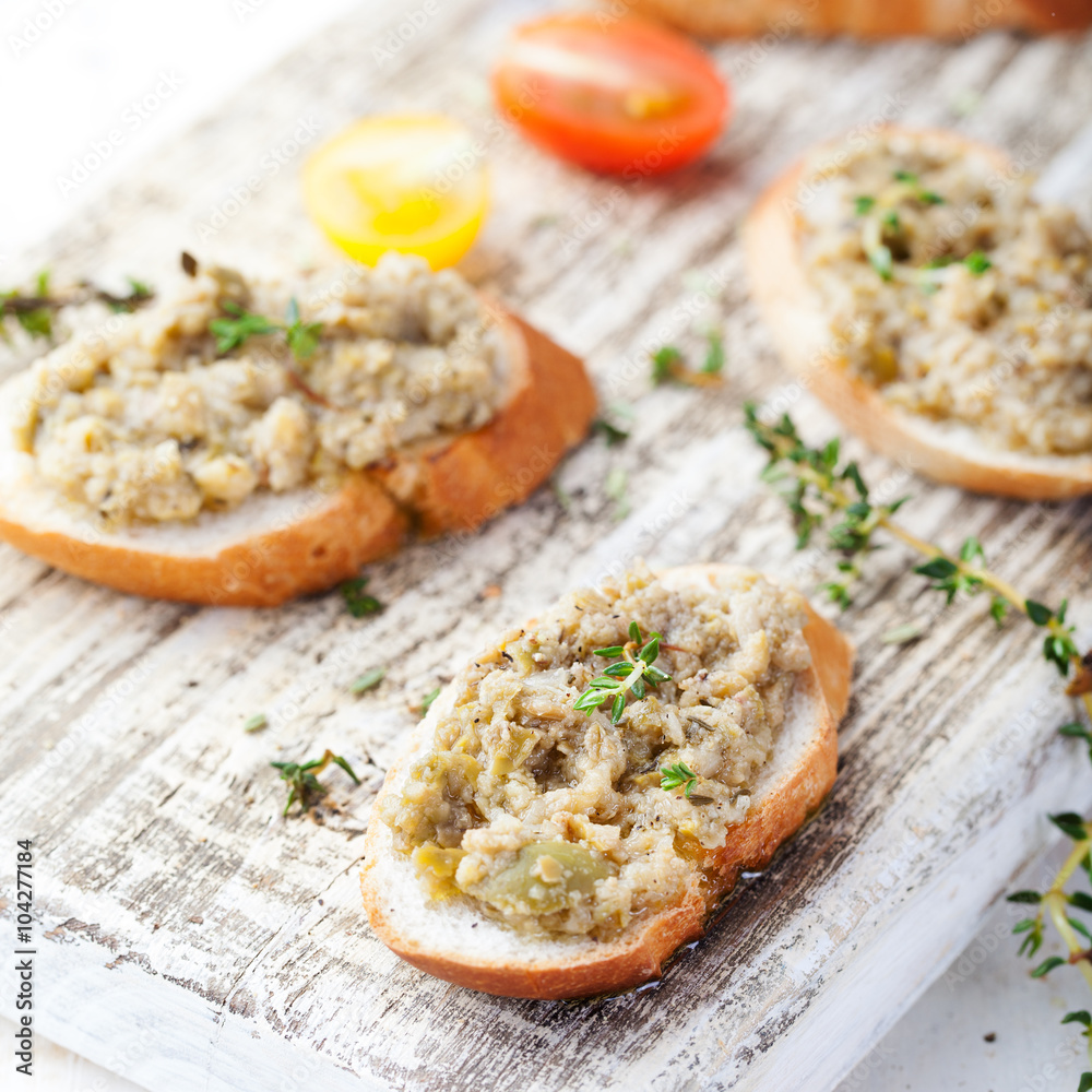 Bruschetta with green olives paste, tapenade on a white wooden background