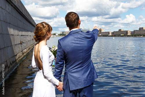 Back view of a romantic couple by the river in summer