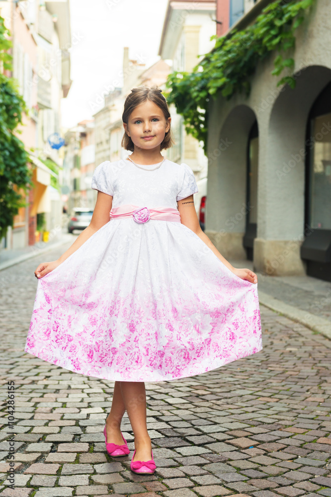 Outdoor portrait of adorable little girl of 7-8 years old, wearing party dress