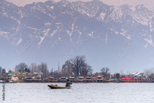 Morning scene of Nigeen lake with the native boat man and the small town behind the mountain range photo