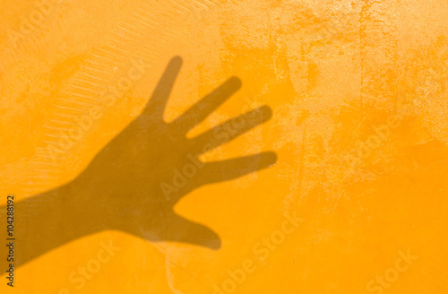 Shadow of hand on yellow wall background