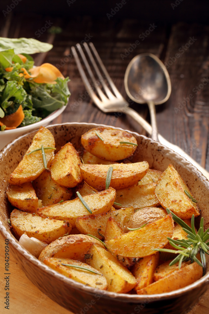 Roasted potato in brown bowl with fresh salad on wooden table Roasted potato in brown bowl with fresh salad on wooden table