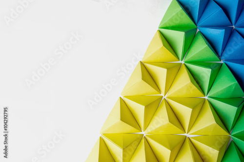 Origami 3 dimension shapes in green, blue and yellow colors with free copy space on the left side. Great for using in web.