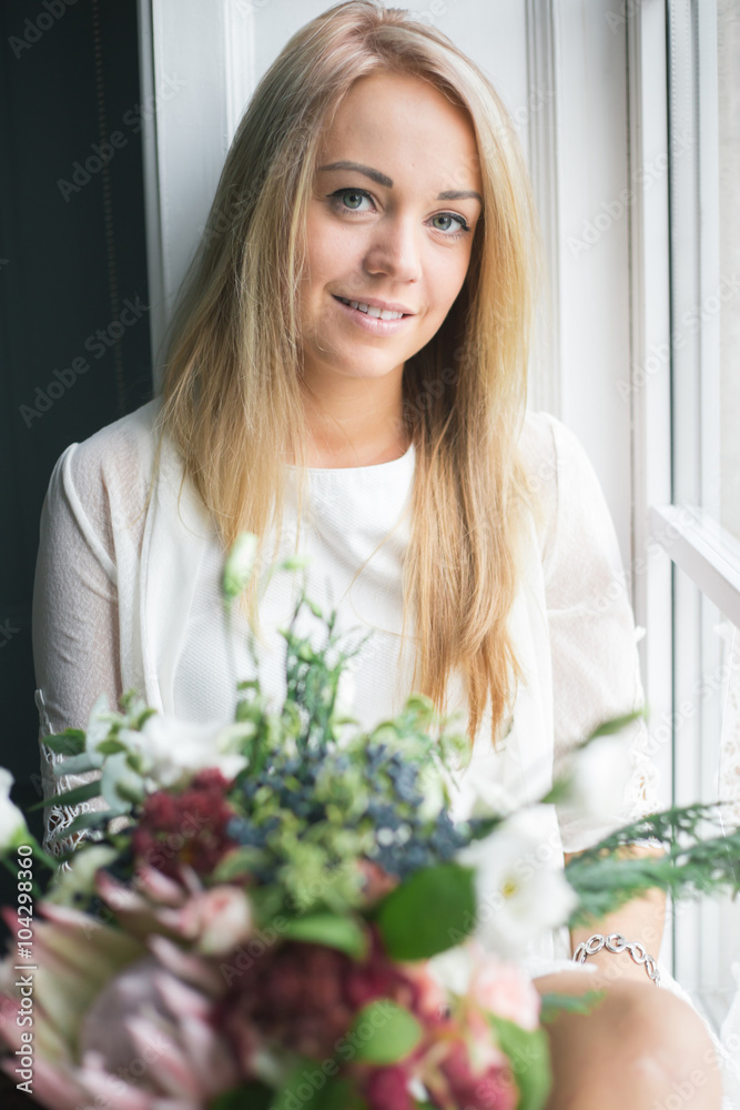 Florist at work: pretty young blond woman holds fashion modern bouquet of different flowers Florist at work: pretty young blond woman holds fashion modern bouquet of different flowers