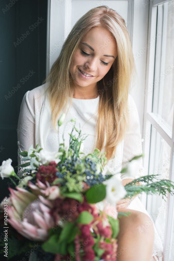 Florist at work: pretty young blond woman holds fashion modern bouquet of different flowers Florist at work: pretty young blond woman holds fashion modern bouquet of different flowers