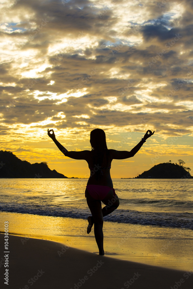 girl in a yoga pose meditating at sunset