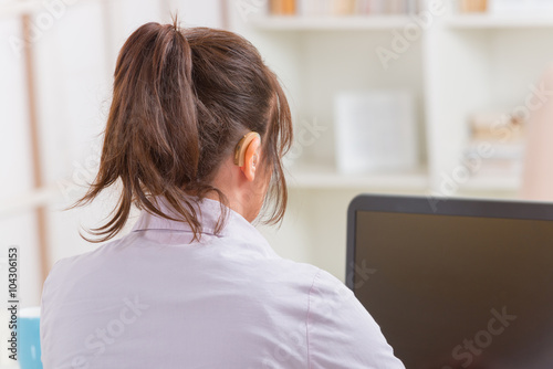 Hearing impaired woman working with laptop photo