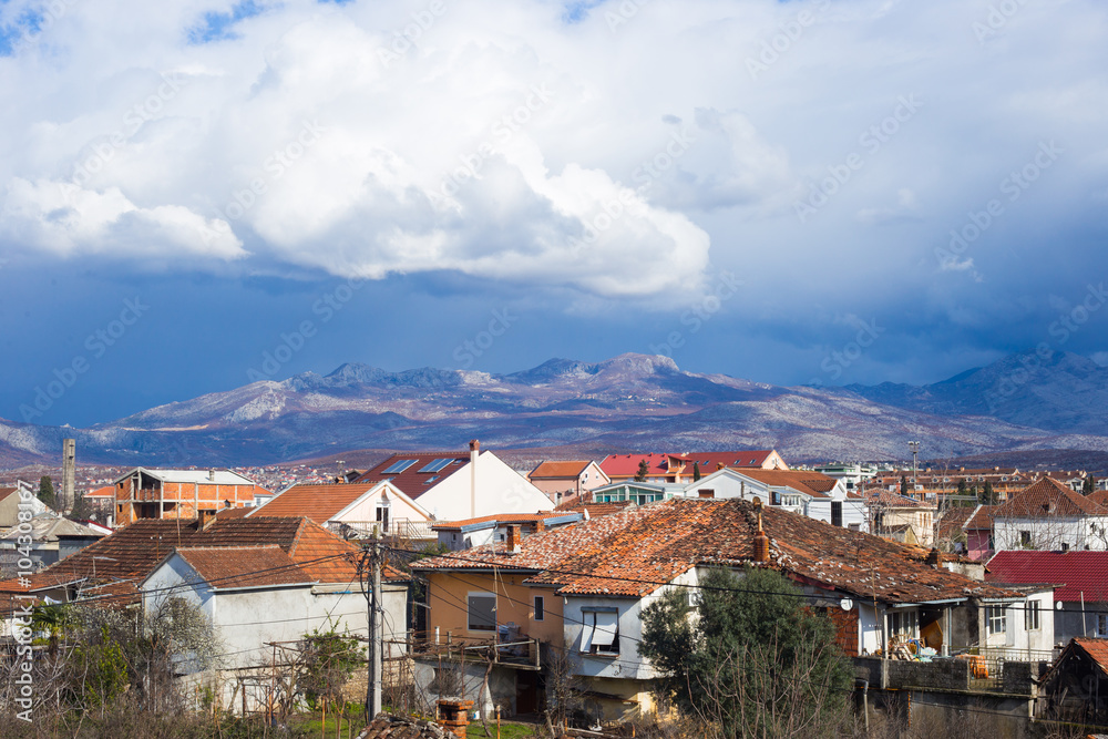 Obraz premium Roofs of Podgorica, Montenegro, mountains and evening sky with clouds