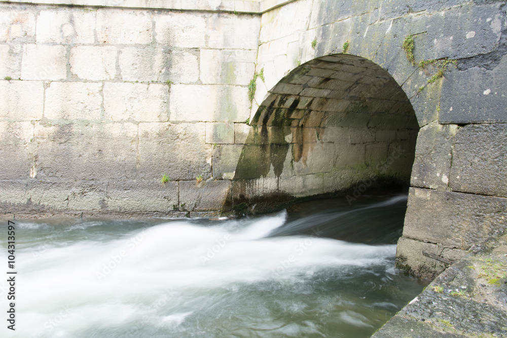 Nebliges Wasser fliesst durch den Tunnel in den Fluss Bach Nebliges Wasser fliesst durch den Tunnel in den Fluss Bach
