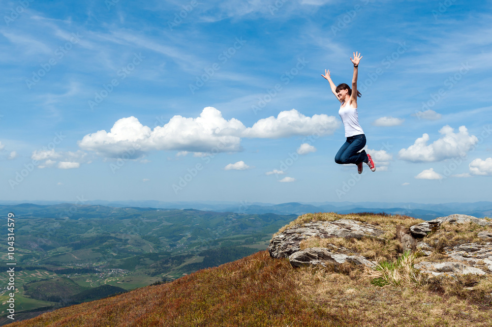 young woman jumping on a background of mountains