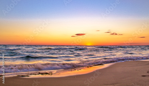 Sunset Beach Panorama. The sunsets on the shores of a wide sandy beach in panoramic orientation.