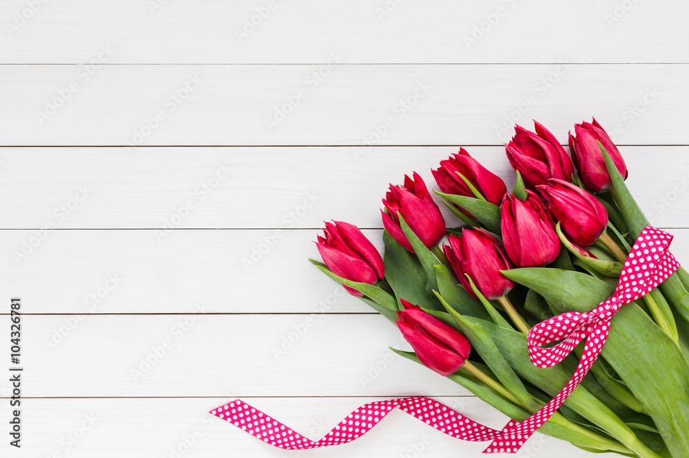 Red tulips bouquet decorated with ribbon. Copy space - obrazy, fototapety, plakaty 