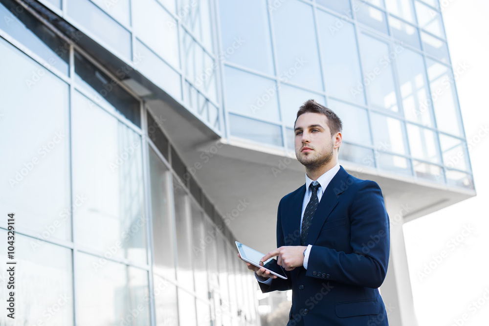 Businessman using a digital tablet computer, standing in front of his office. Businessman using a digital tablet computer, standing in front of his office.