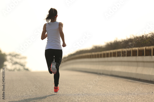 young fitness woman runner running on sunrise road
