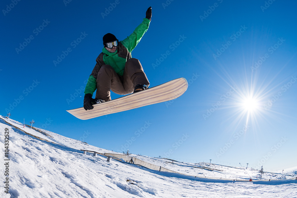 Snowboarder jumping against blue sky