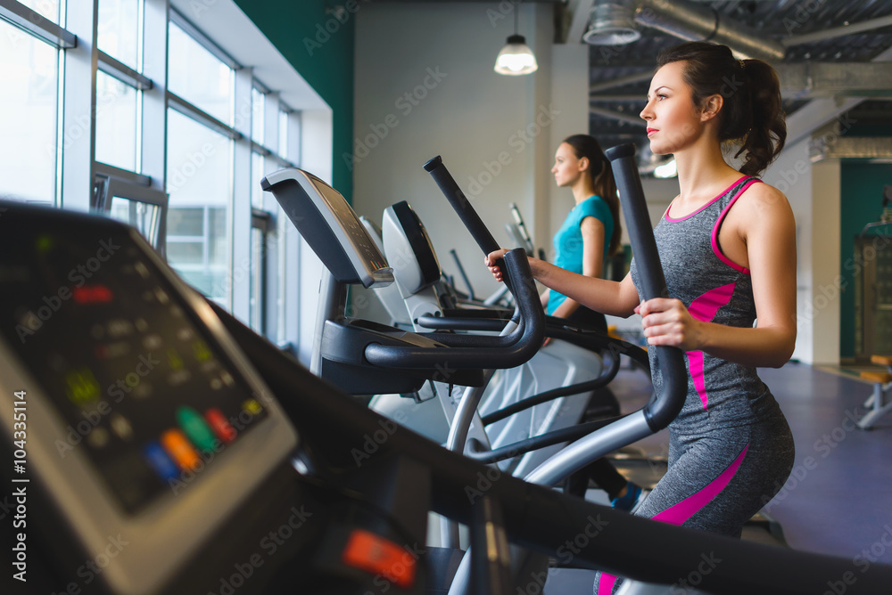 Fototapeta premium Woman exercising at the gym on a cross trainer