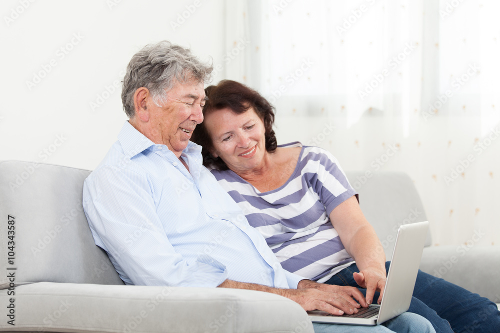 Senior couple laughing while using laptop Senior couple laughing while using laptop