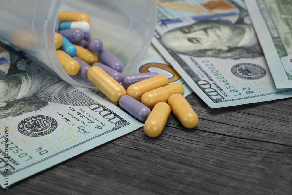 Scattered Colorful Pills and Capsules on Money on Wooden Table Scattered Colorful Pills and Capsules on Money on Wooden Table
