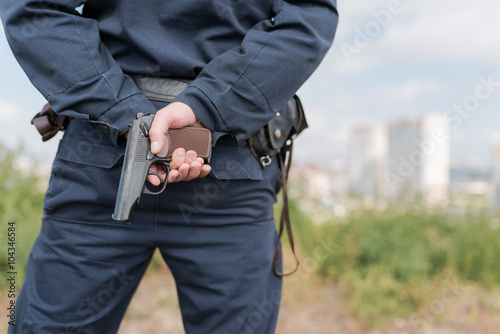 Detail of a police officer holding gun. Selective focus with shallow depth of field.