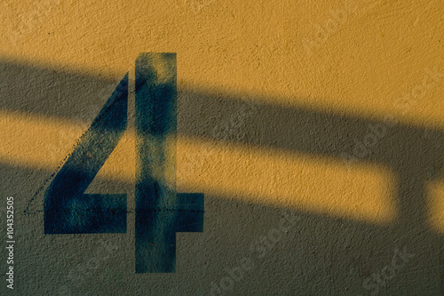 the number 4 on the wall under the shadow of the lights photo