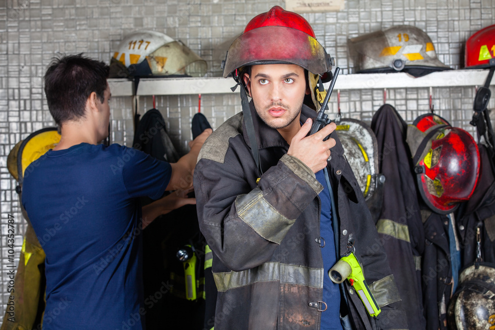 Firefighter Using Walkie Talkie With Colleague In Background Stock