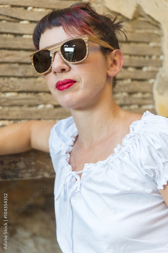Woman in white wearing red lipstick and wooden sunglasses. Woman in white wearing red lipstick and wooden sunglasses.