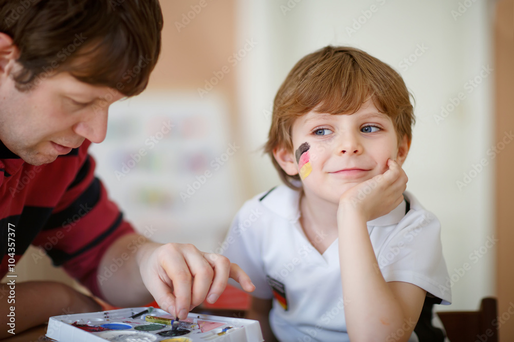 Fototapeta premium Father painting flag on face of little kid for football or socce