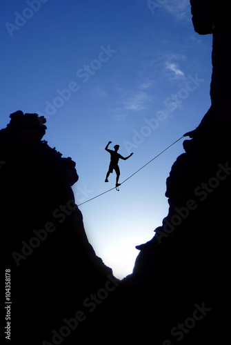 Man walking on tight rope over the rock