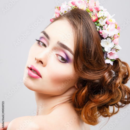 Close-up portrait of beautiful young woman with perfect make-up and hair-style with flowers in hair