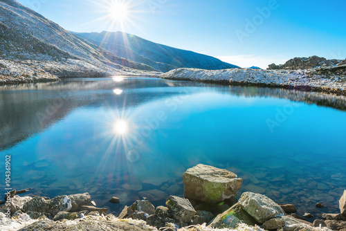 Fototapeta Naklejka Na Ścianę i Meble -  Beautiful blue lake in the mountains, sunset time. Landscape with sun and reflection in water