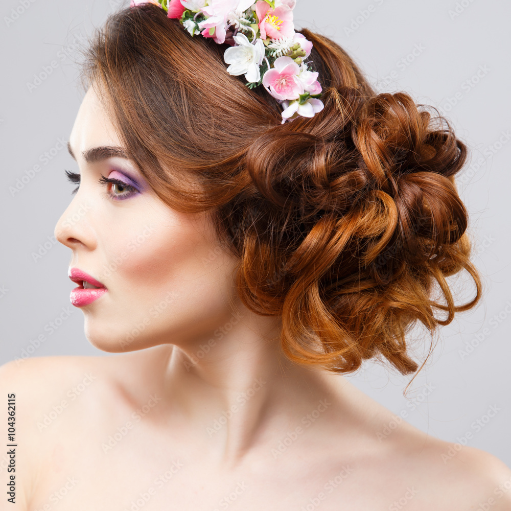 Naklejka premium Close-up portrait of beautiful young woman with perfect make-up and hair-style with flowers in hair