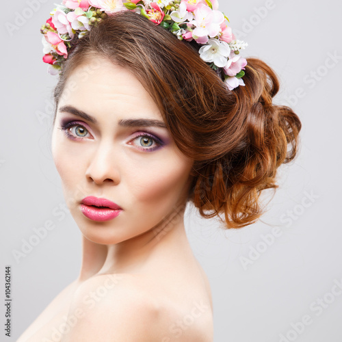 Close-up portrait of beautiful young woman with perfect make-up and hair-style with flowers in hair