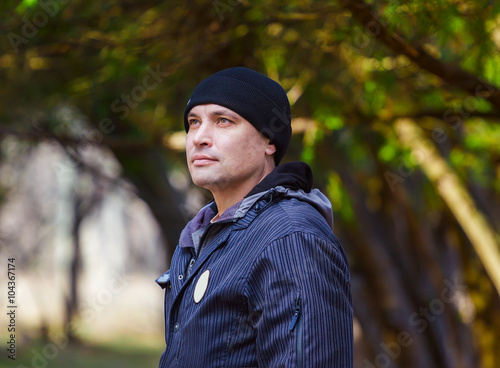 Attractive smiling man breathing fresh spring air and admiring landscape, walking in the forest 