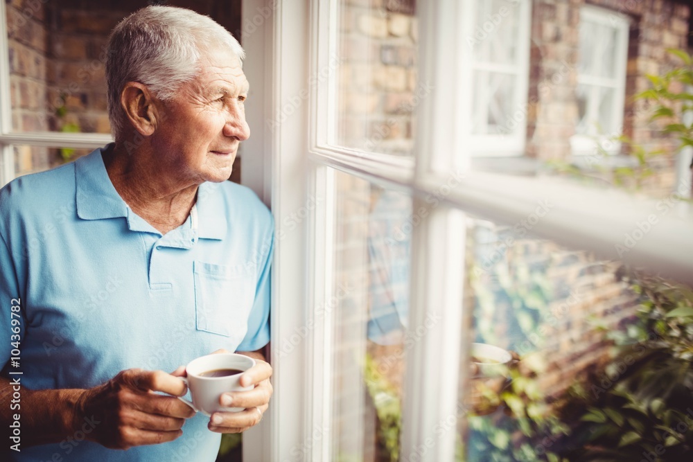 Senior man holding cup and looking out of the window Senior man holding cup and looking out of the window
