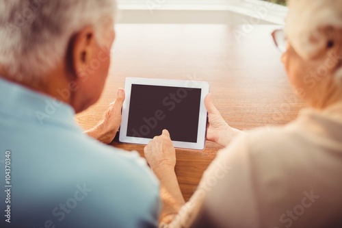 Fototapeta Naklejka Na Ścianę i Meble -  Rear view of senior couple using tablet