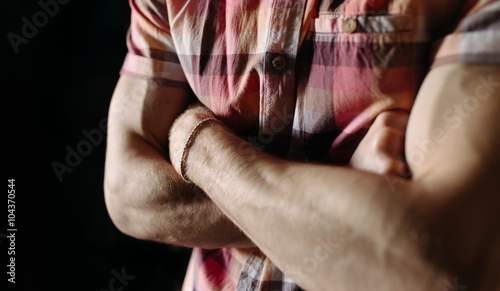 Arms crossed. Strong hands of male in a checkered shirt close up