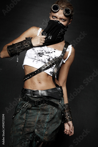 Young woman in brutal style clothes with goggles on studio black background