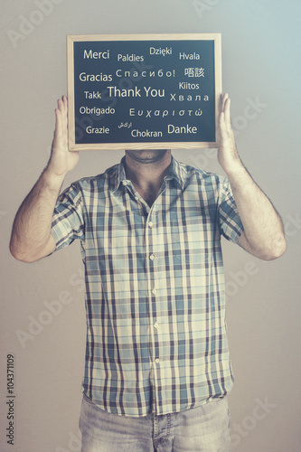 Man expressing his gratitude holding a Thank You message board written in many different languages